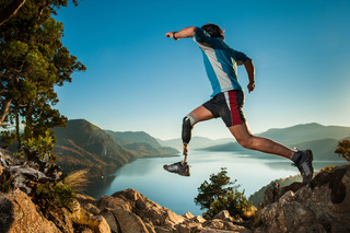 Person leaping across rocks above a lake